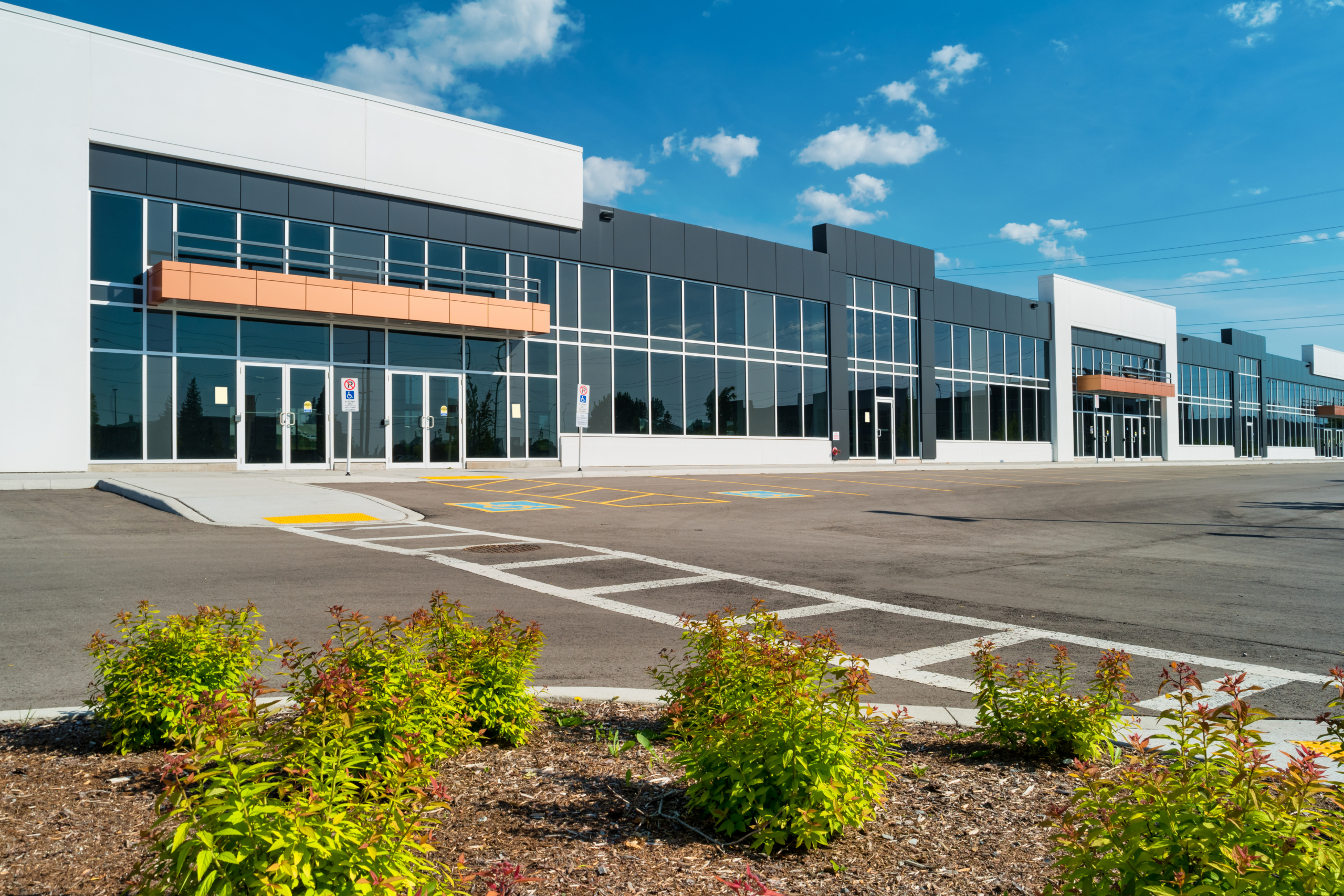 Modern commercial building with glass frontage and empty parking lot